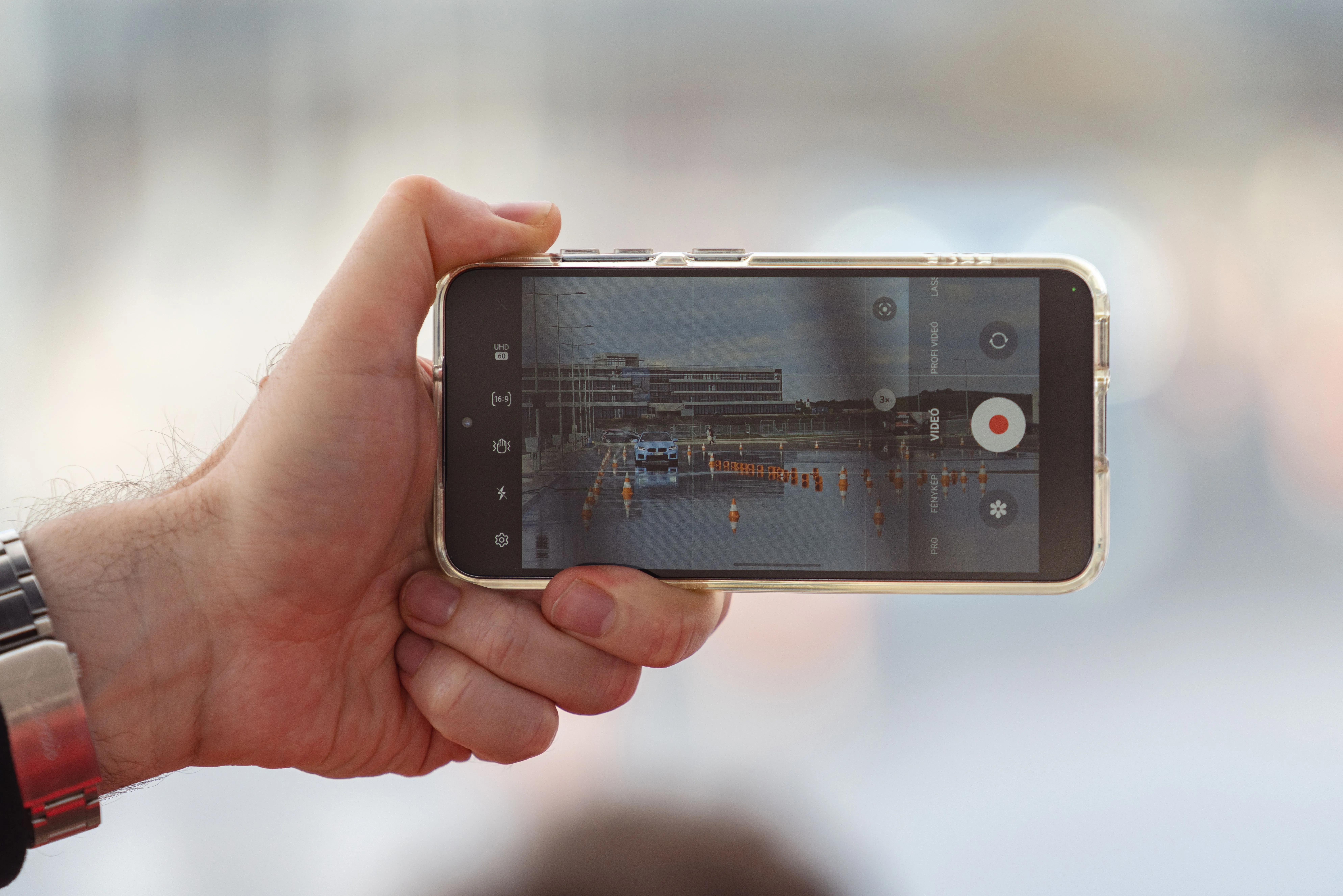 A hand holding a phone recording video, the entire production budget most coaches actually need