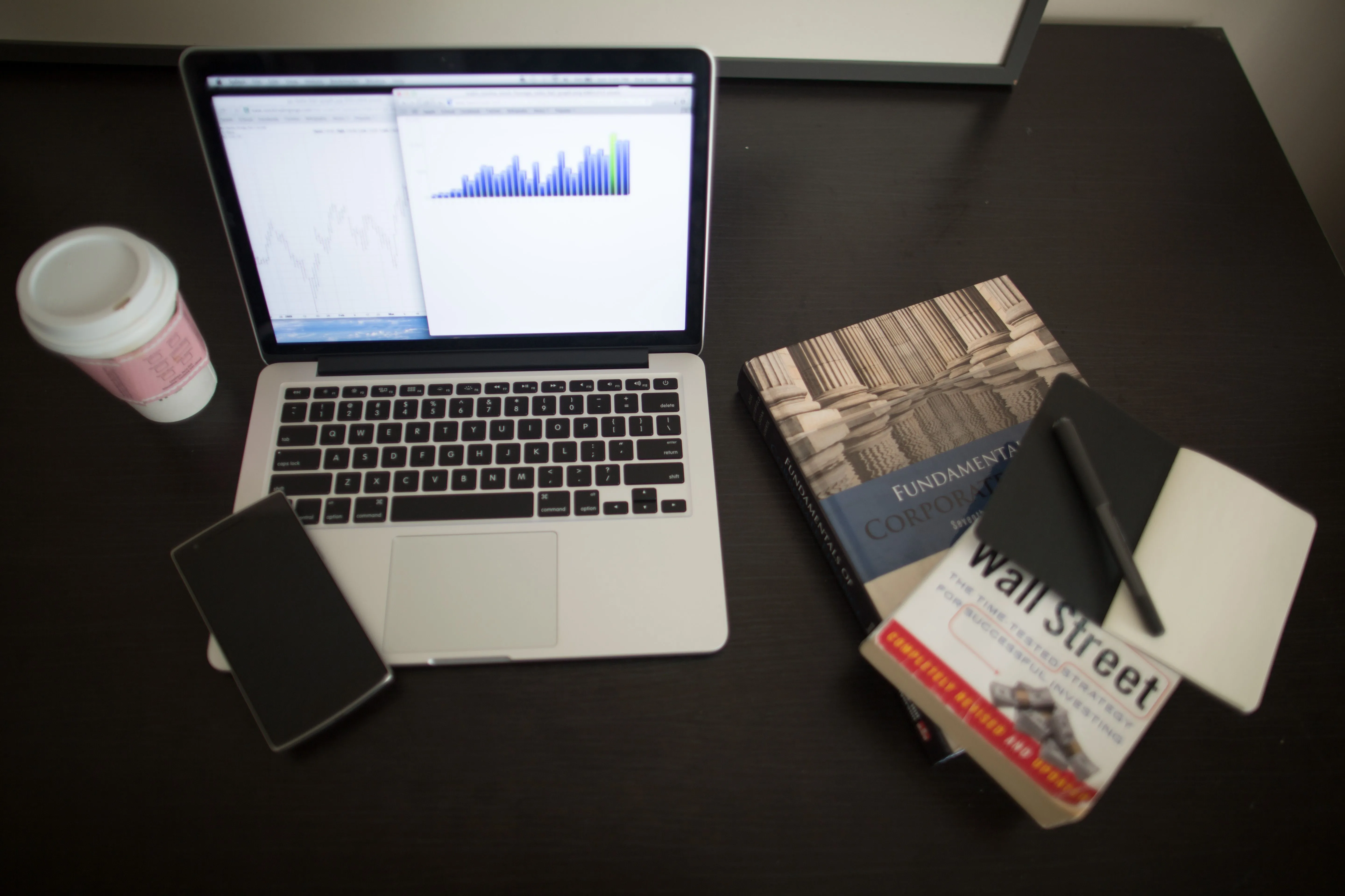 A laptop, notebook, and coffee on a table, the quiet setup behind a consistent newsletter habit
