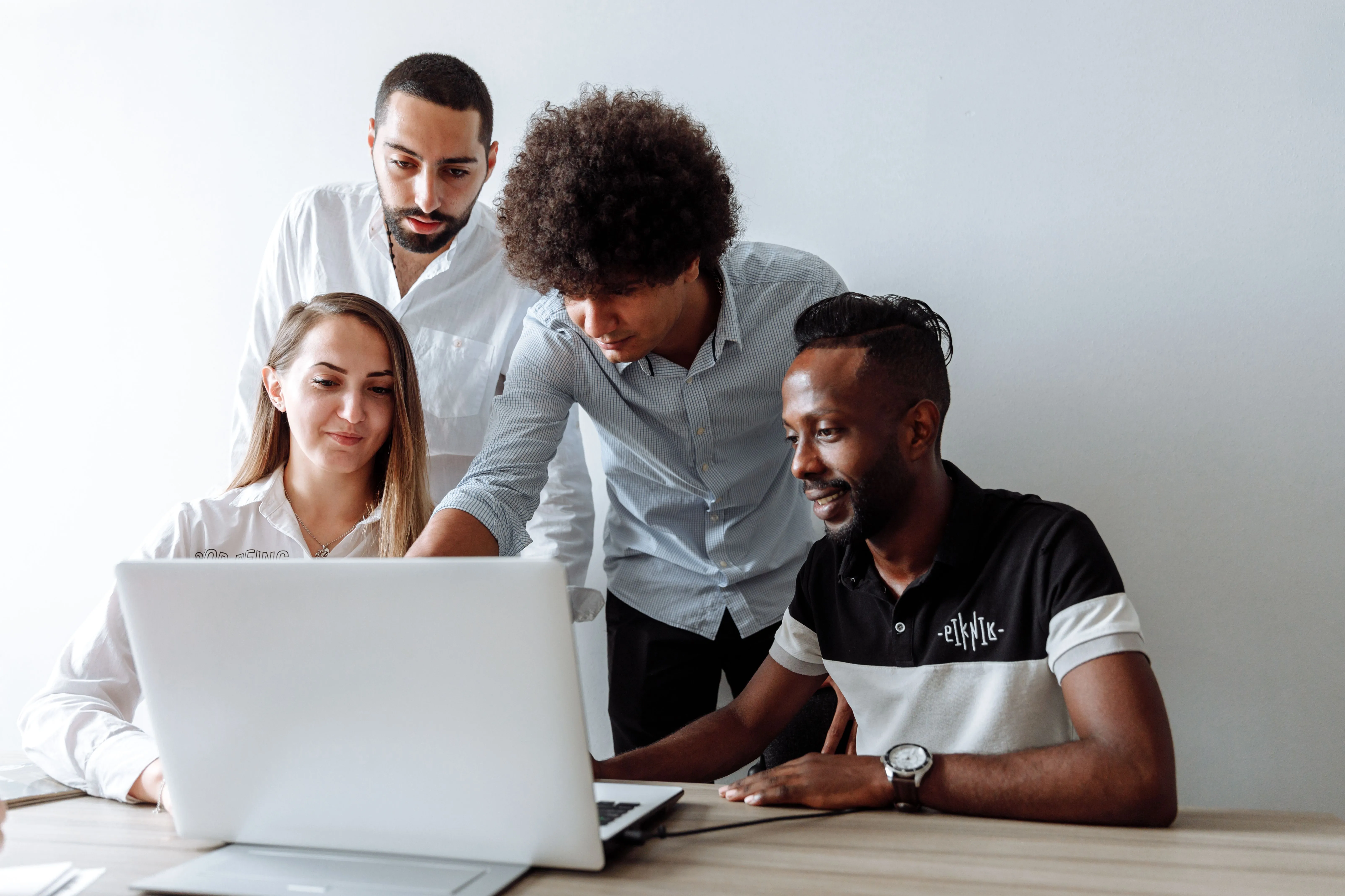 A group reviewing work together at a laptop, the collaborative judgment behind an editorial yes
