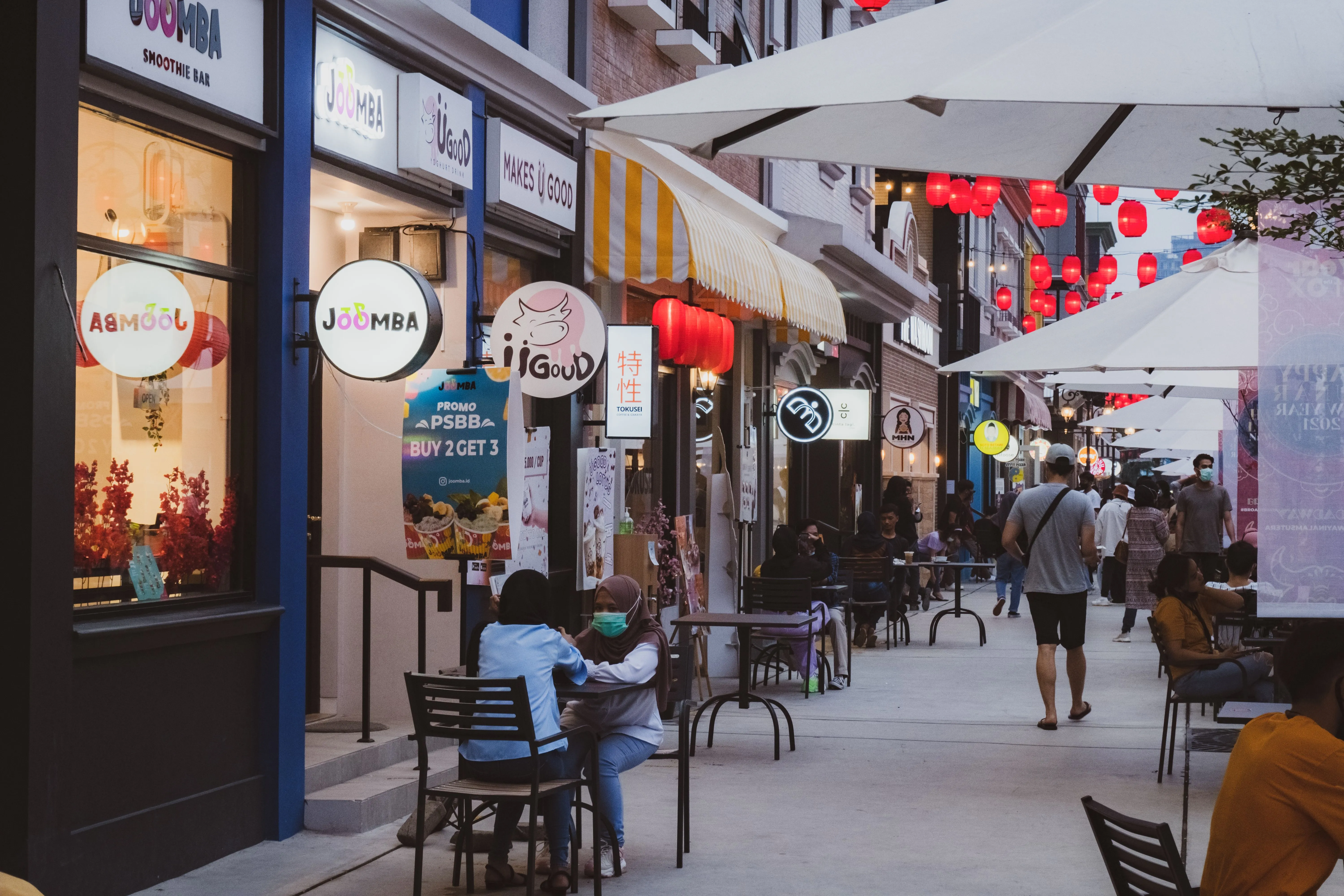 Illuminated storefronts along a sidewalk at night, the local businesses an AI has to choose between
