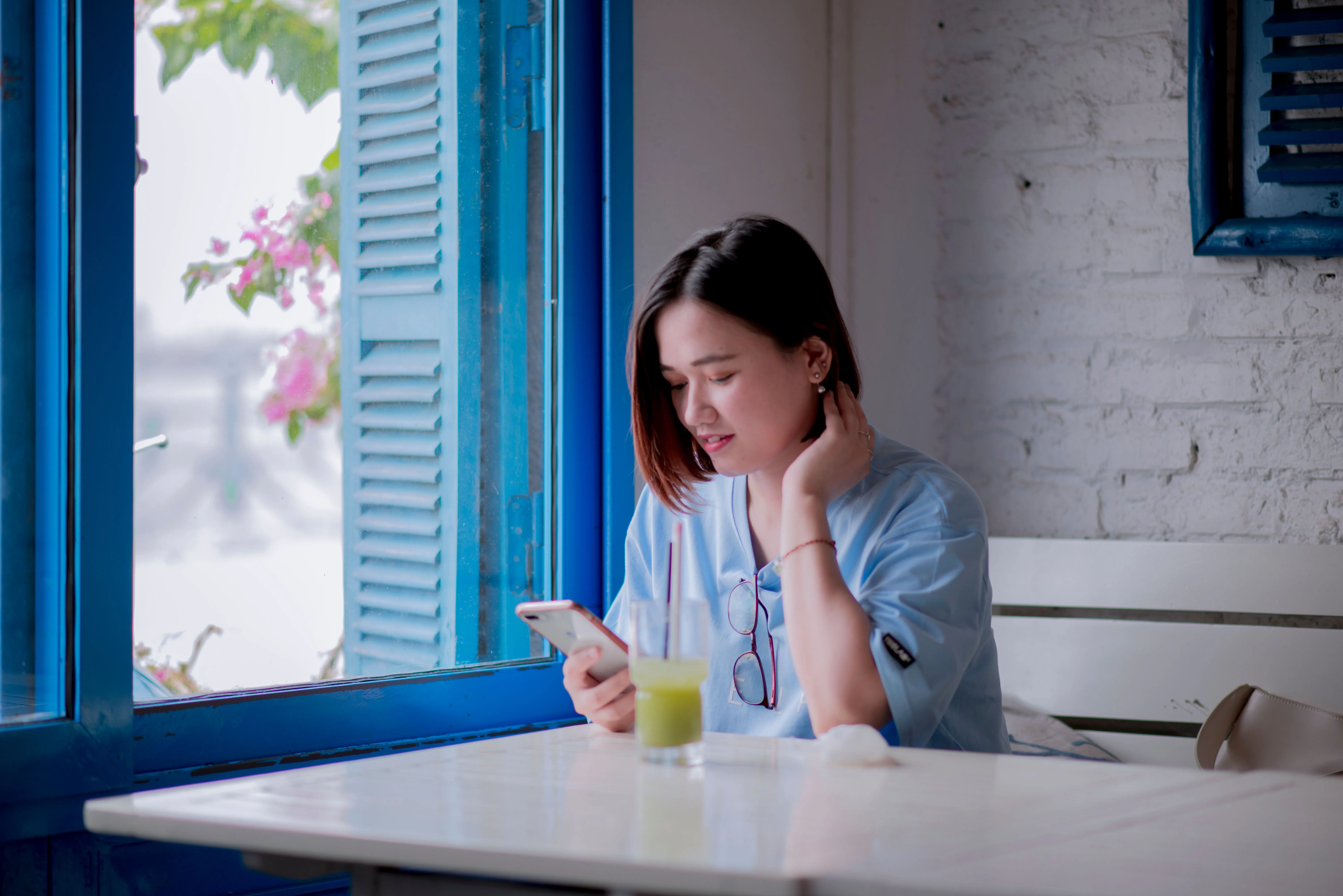 A woman checking her phone in a cafe, the screen where most gym reputations are actually decided