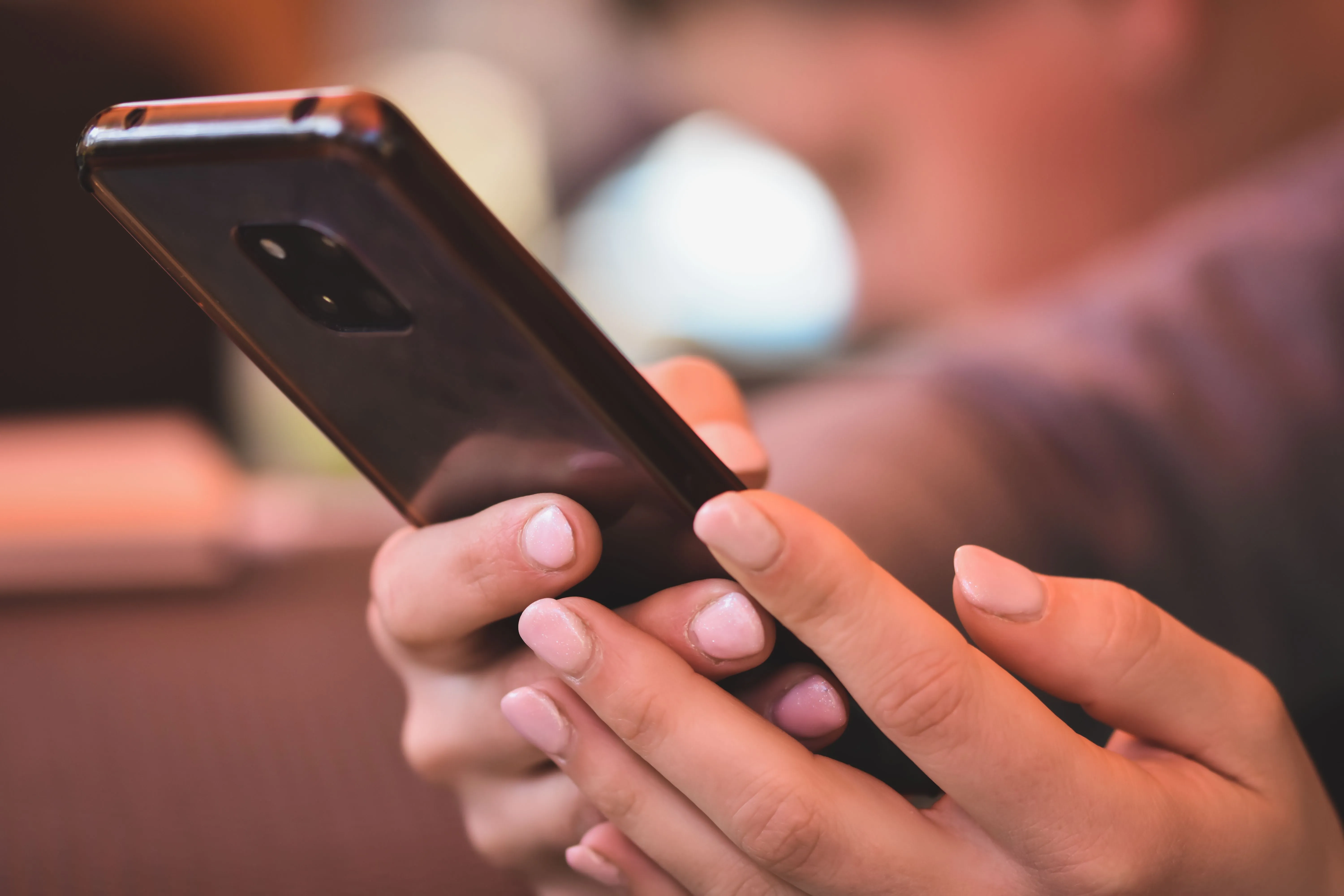 A person smiling while using their phone, caught at the moment of satisfaction