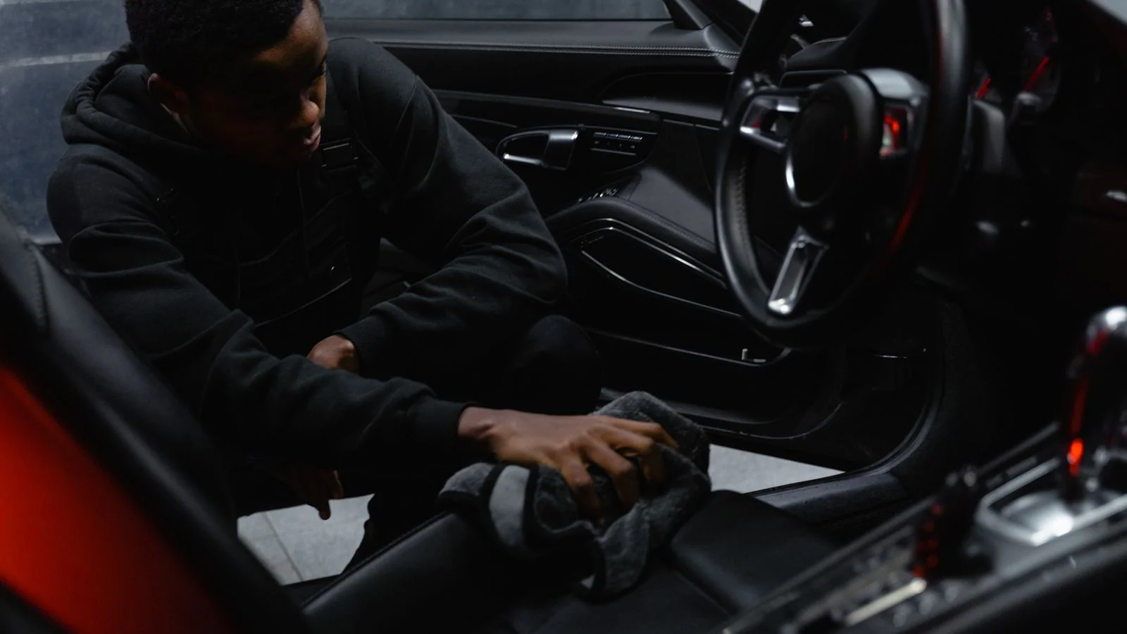 A person carefully wiping down and cleaning the interior of a car during a detail.