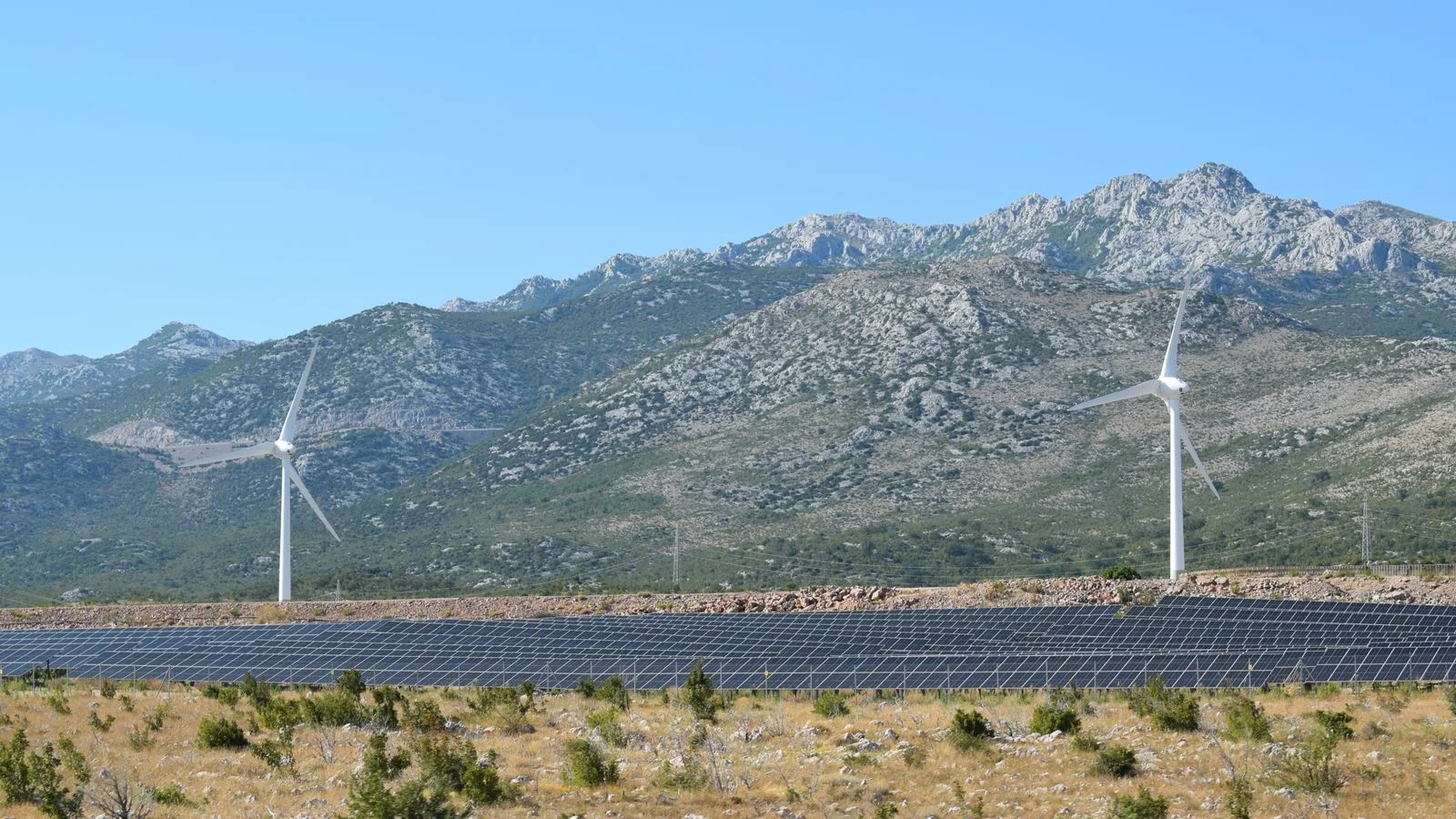Wind turbines and solar panels across a green valley, the measurable impact cleantech must prove