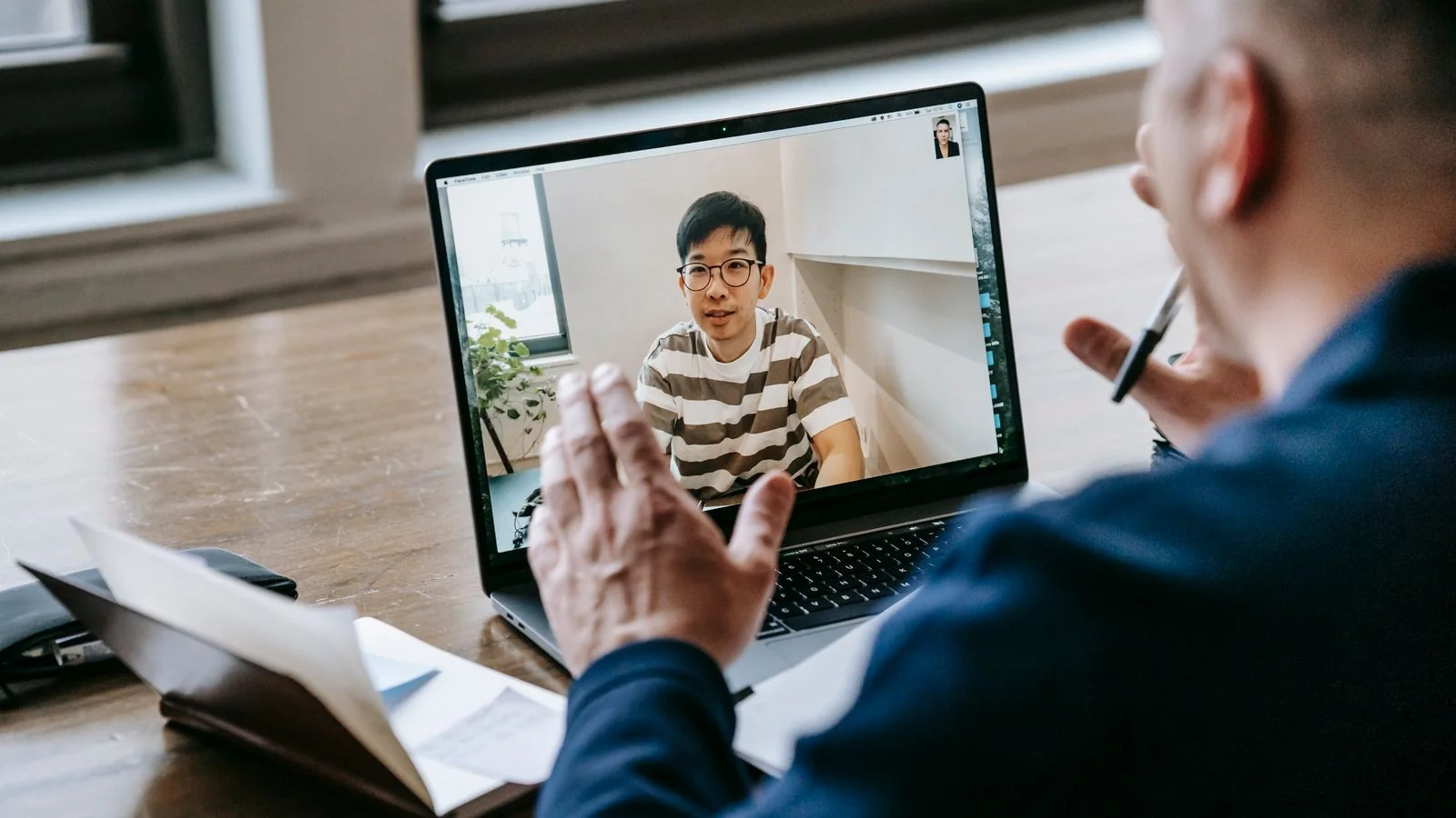 Two professionals meeting over a laptop video call in a bright indoor space