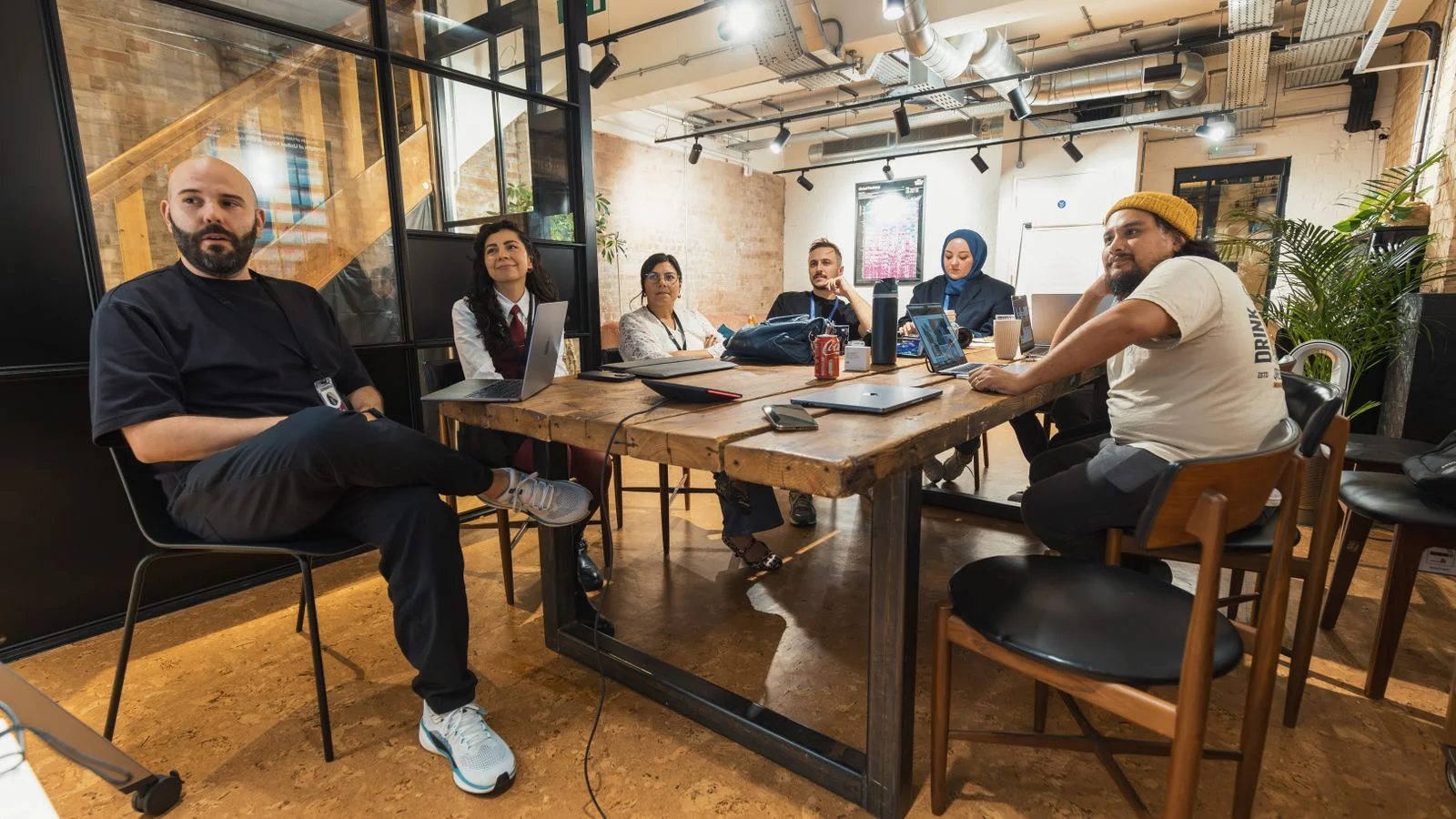 A team collaborating around a table with open laptops in a contemporary office