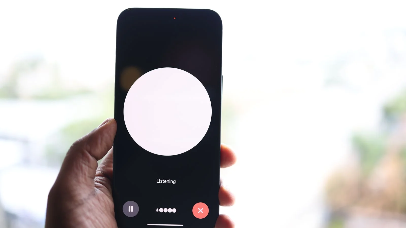 A hand holding a phone with a voice assistant open, how the question often gets asked