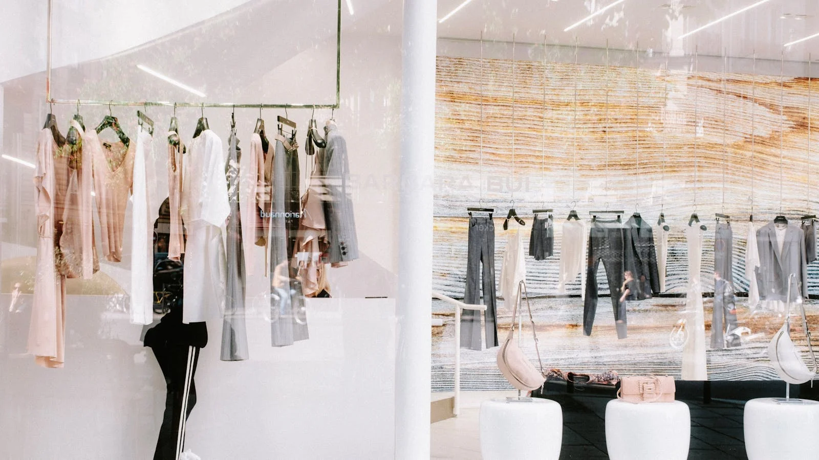 A row of clothes hanging on racks inside a stylish boutique with reflective surfaces.