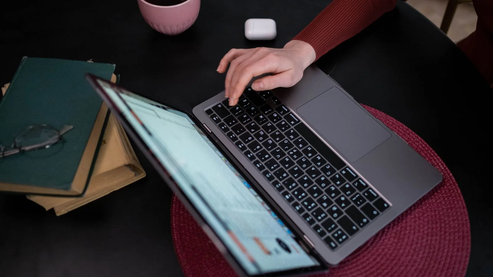 A person typing a question into a laptop at a desk.