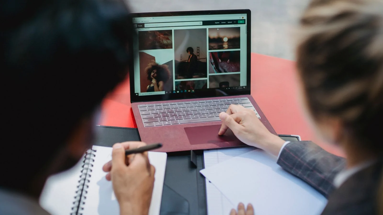 Two professionals reviewing details on a laptop, the kind of listings audit AEO depends on.