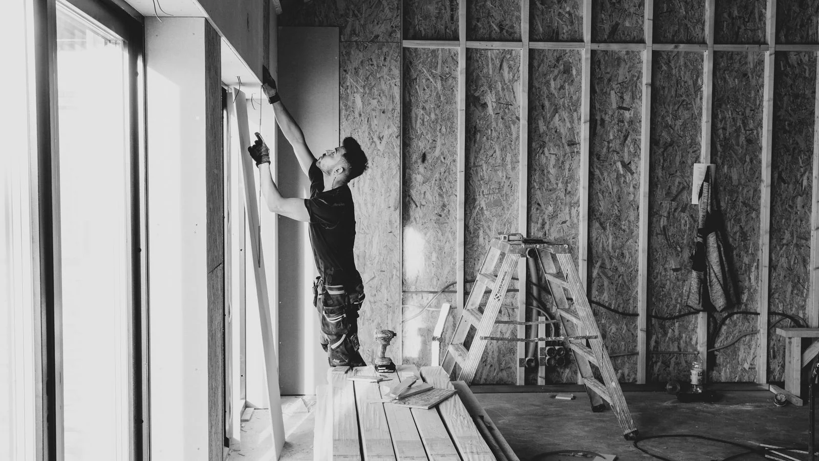 Worker installing drywall in an unfinished room, the construction phase homeowners ask AI about before hiring.