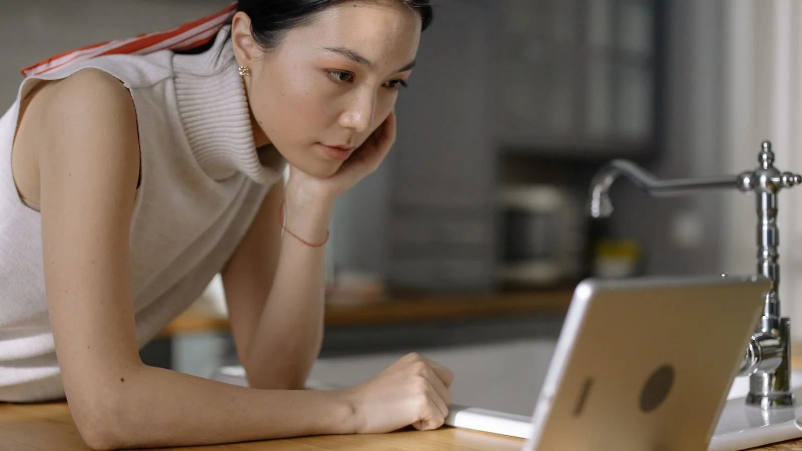 Homeowner leaning on a kitchen counter using a tablet, typing the questions that become pages.