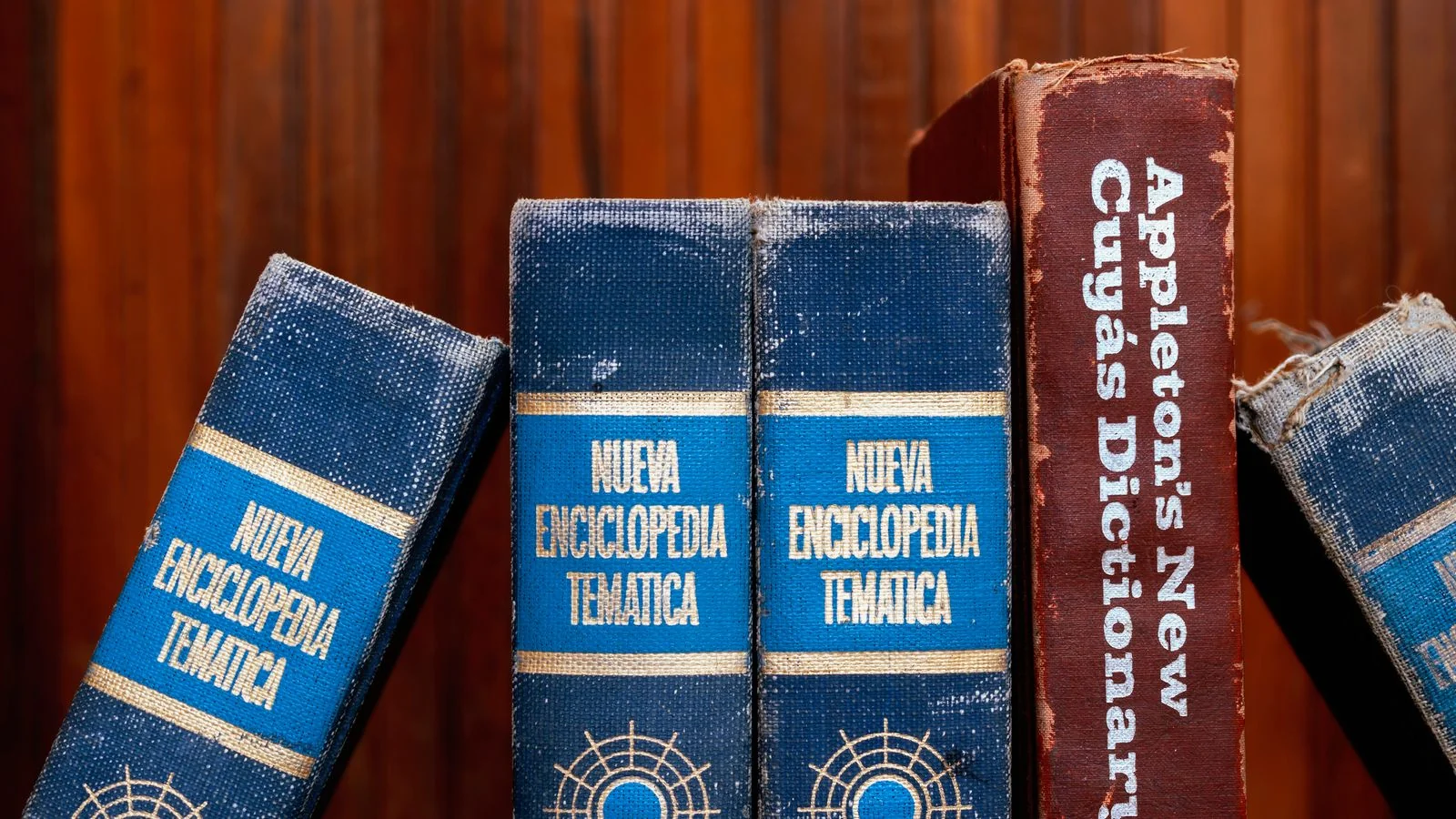 Old dictionaries and encyclopedias on a wooden shelf, the reference work a page has to replace
