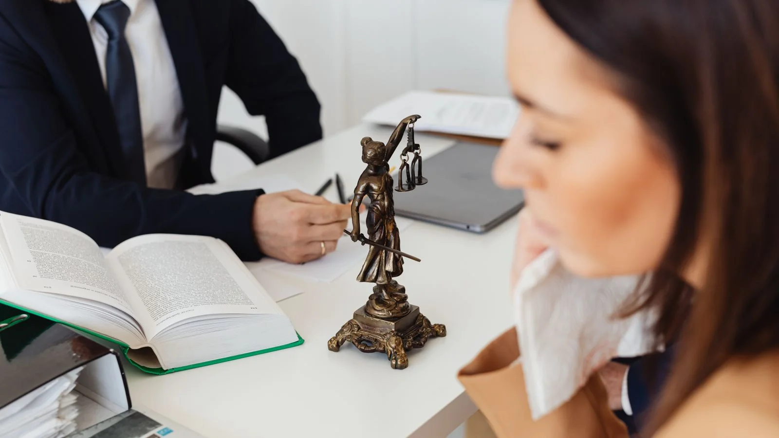Attorney consulting with a client across a desk, the conversation a well-built answer page initiates