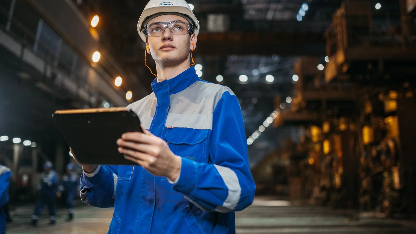Engineer using a tablet on the factory floor, checking the structured capability data that AI search now reads