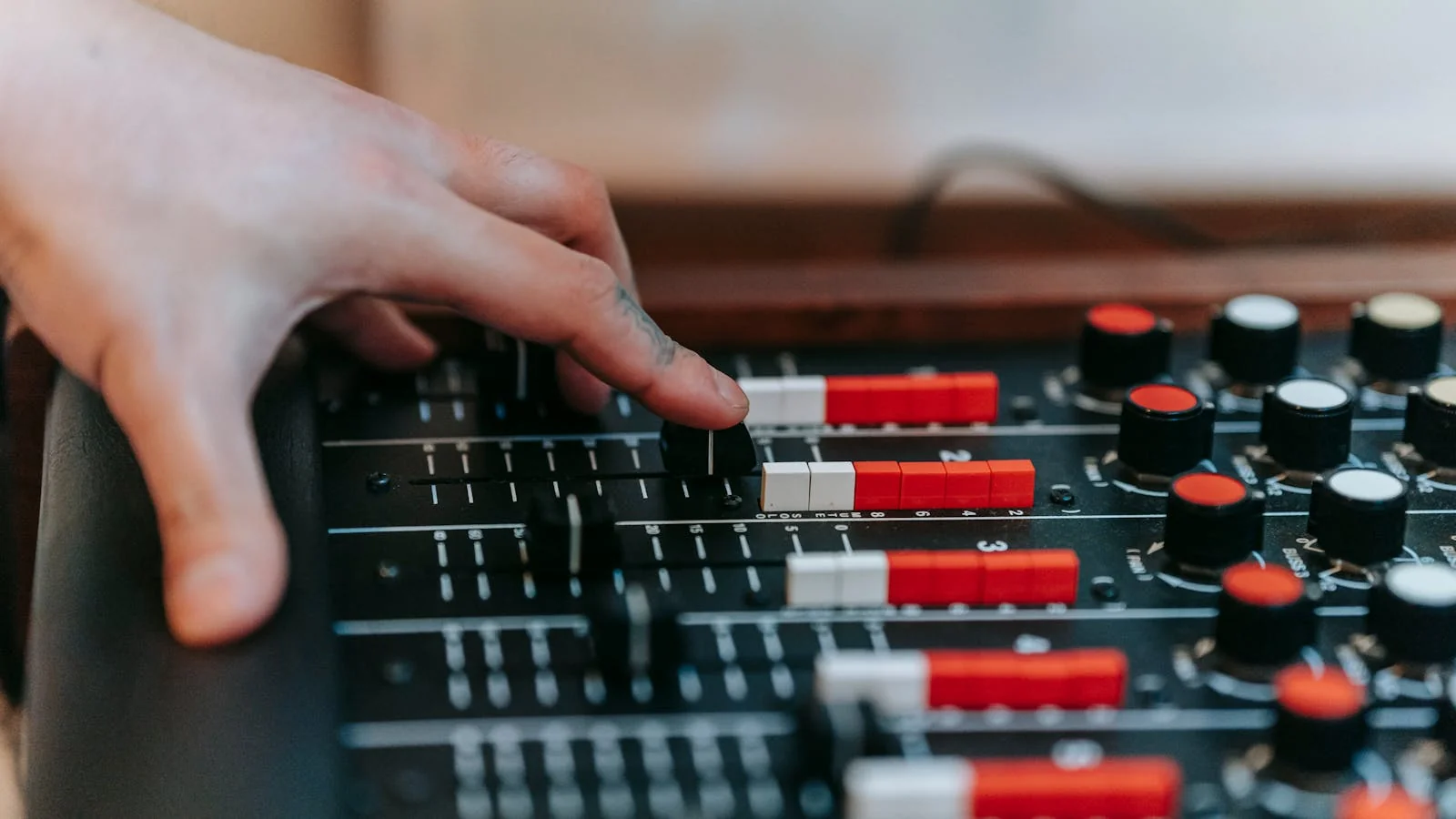 A hand adjusting the controls on a studio mixing console