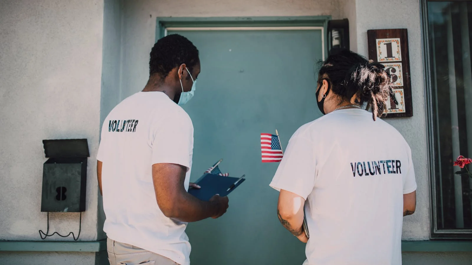 Two volunteers in white shirts visiting homes for community outreach