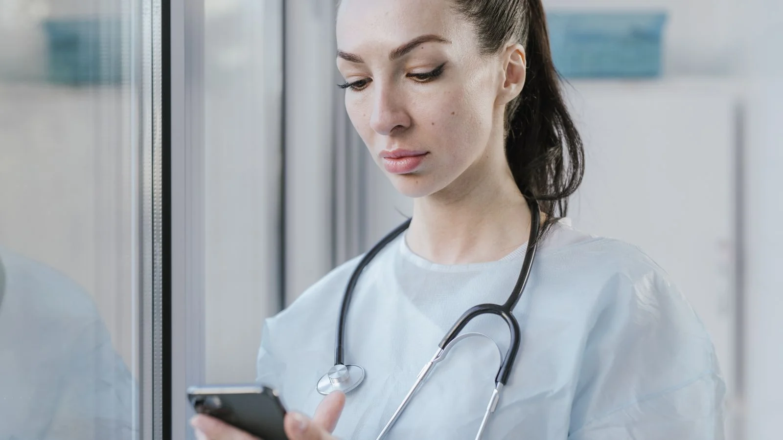 A healthcare professional checking a smartphone in a clinical setting, mirroring how patients search for a physical therapist