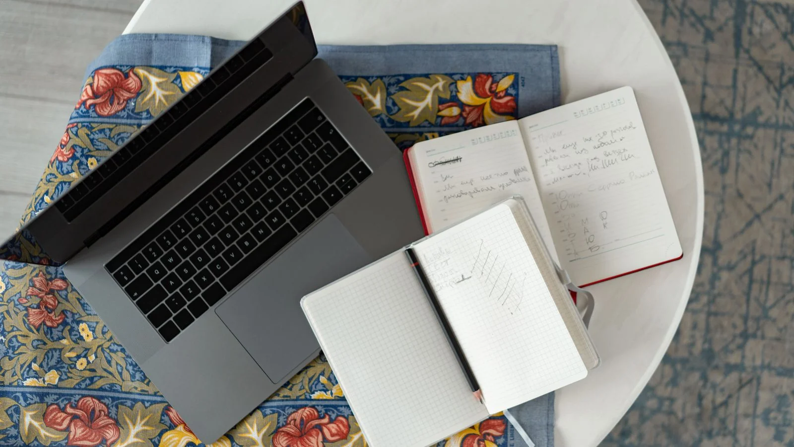 An open notebook beside a laptop on a wooden desk