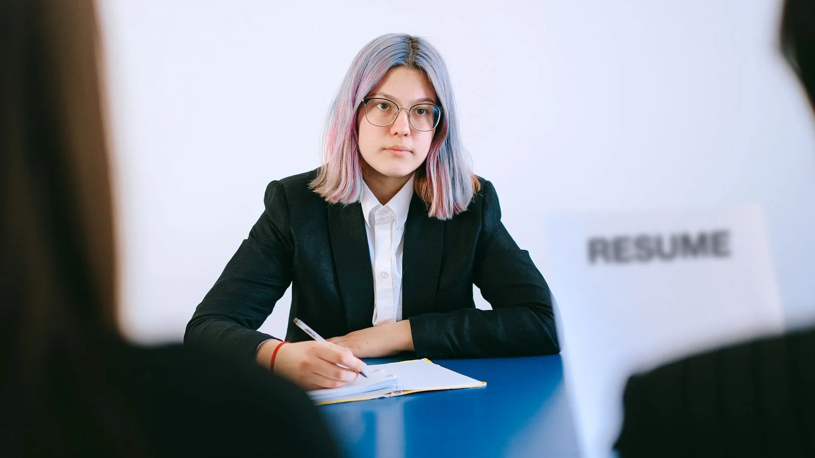 Candidate in a suit taking notes across the table during a staffing interview