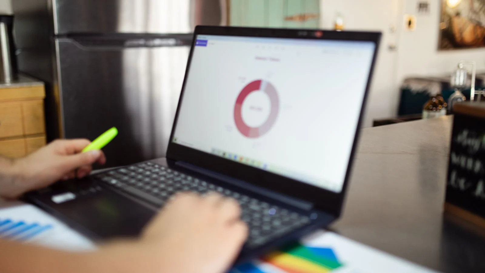 A person analyzing data and charts on a laptop in a modern setting.