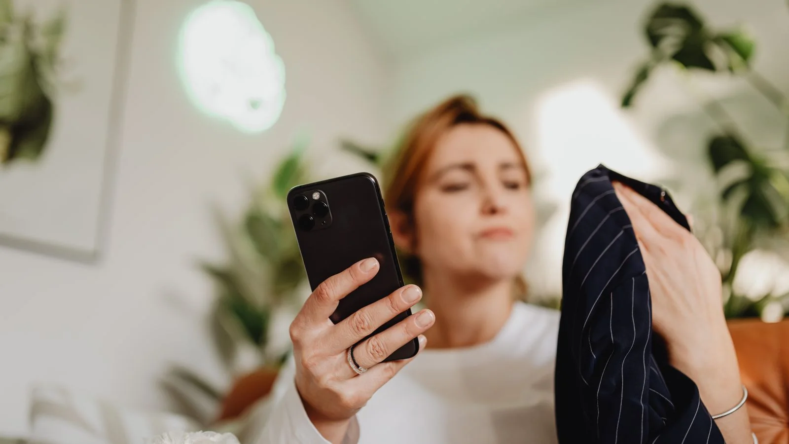 A woman checking her phone indoors, the question an assistant answers before your studio gets a chance