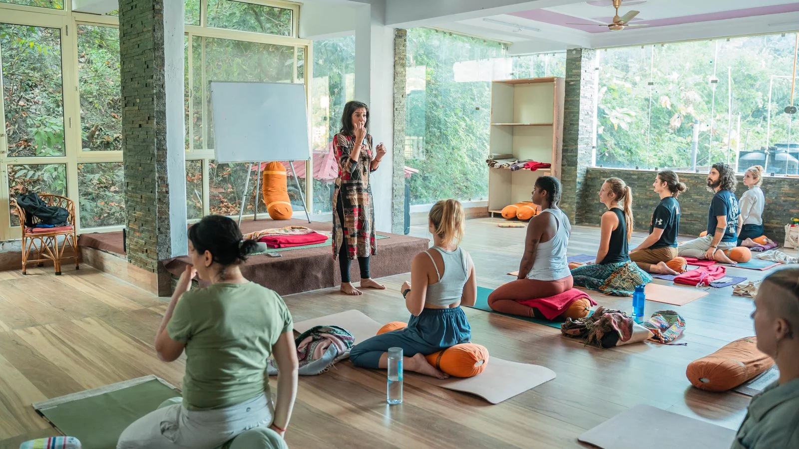 A yoga teacher leading a group in a calm studio, the specific teaching experience assistants need described in words