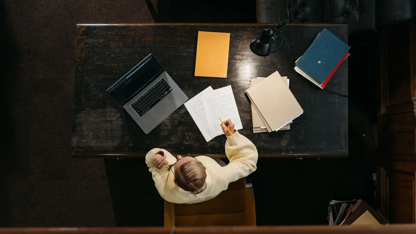 Writer in a yellow sweater working through documents at a desk, the human drafts detectors misread