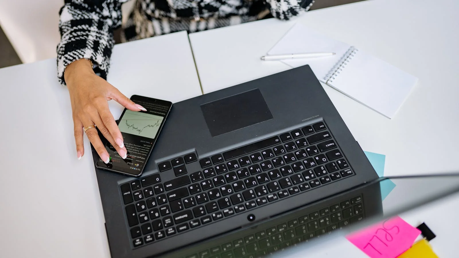 Hands working across a laptop and phone, the moment a customer reads an AI verdict on a brand