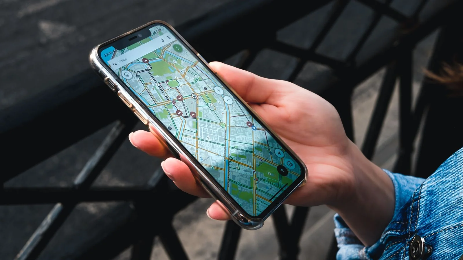 A hand holding a smartphone showing a maps and navigation app on a city street