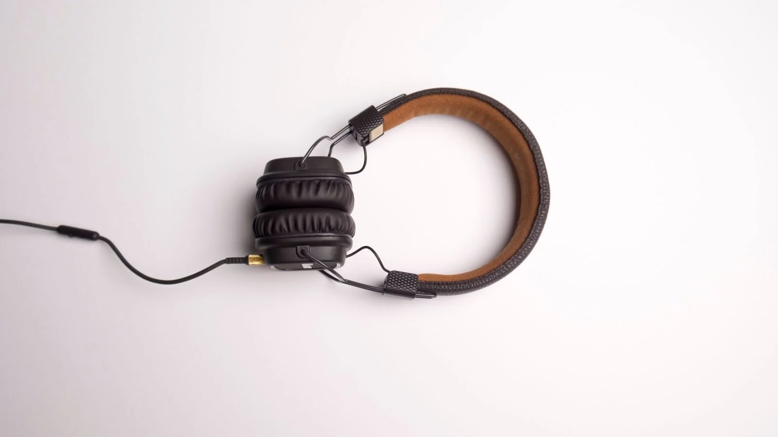 Studio over-ear headphones on a clean white surface, the kind a producer wears while reviewing a finished transcript