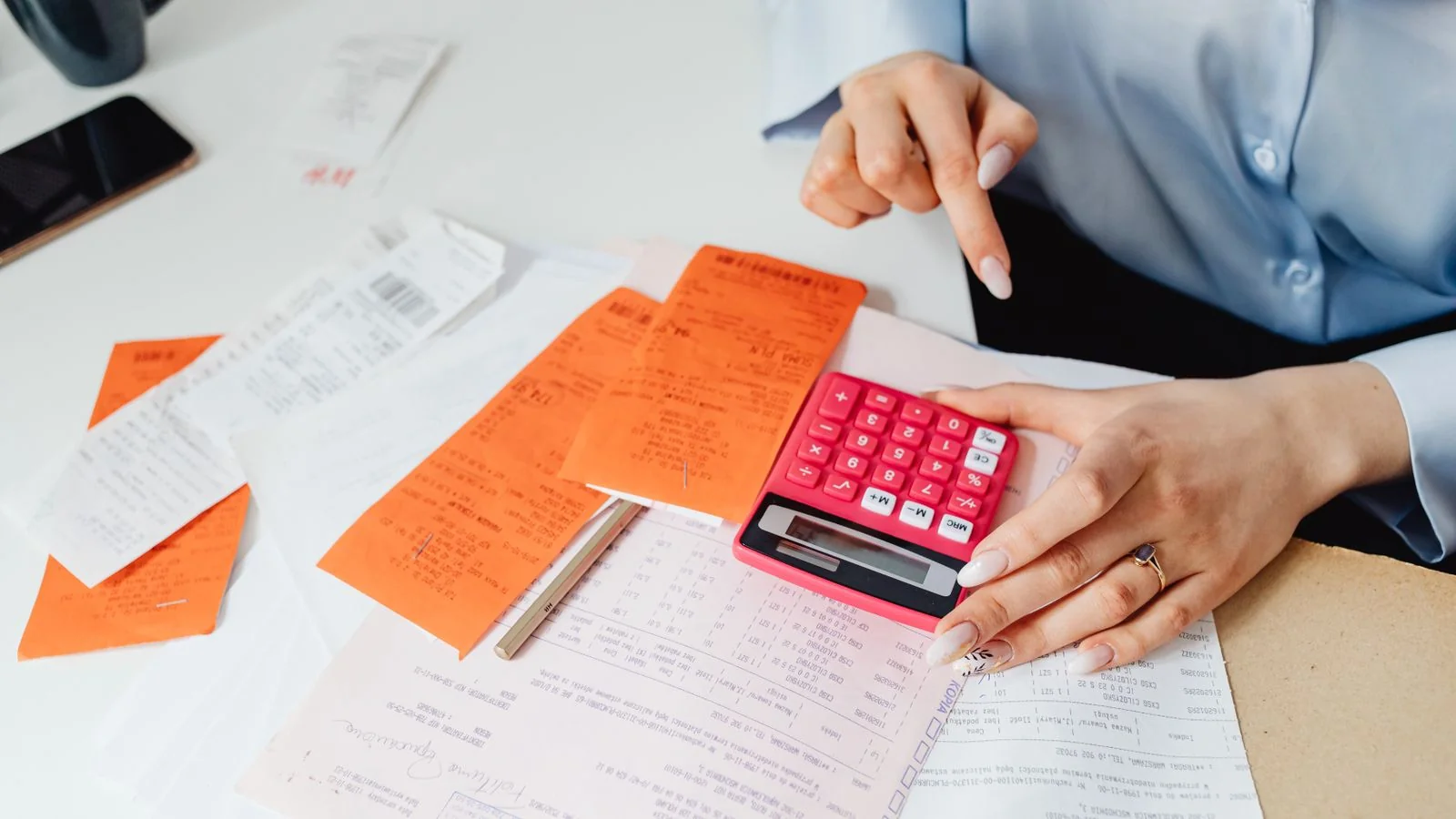 Person pricing out software plans with a calculator and a stack of receipts at a desk