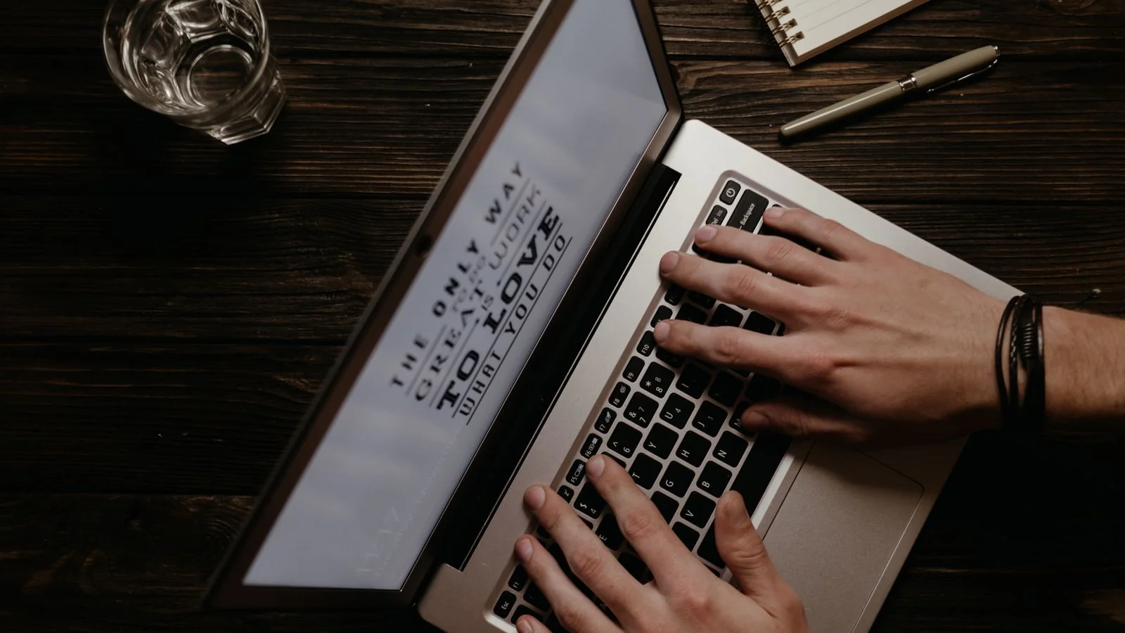 A person writing and editing an article on a laptop, shot from above