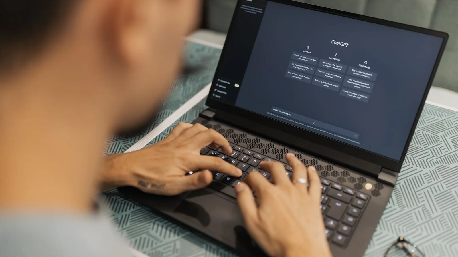 A focused person working on a laptop with an AI assistant on the screen