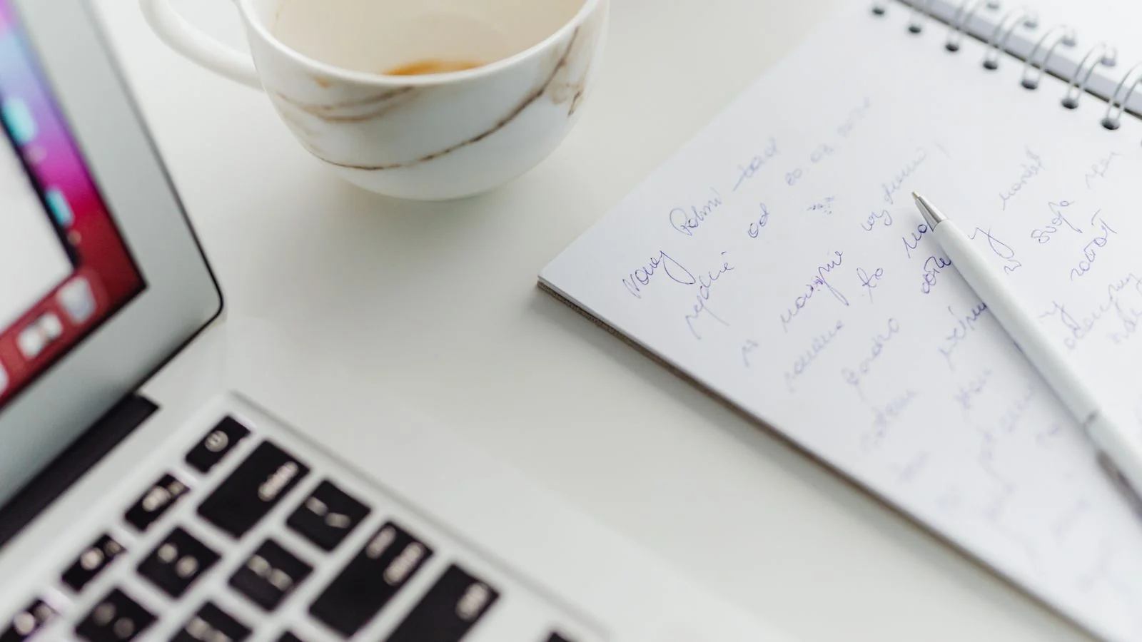 Laptop, notebook and coffee cup on a tidy desk, ready for drafting a press release