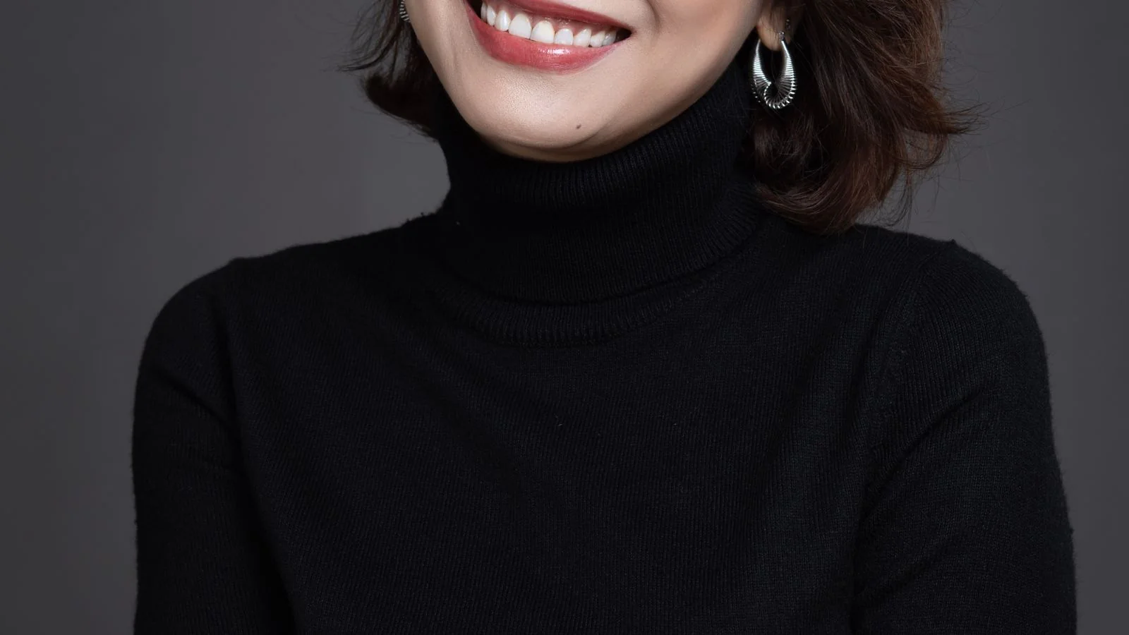 A smiling woman in a black turtleneck, a recognizable character an archetype creates
