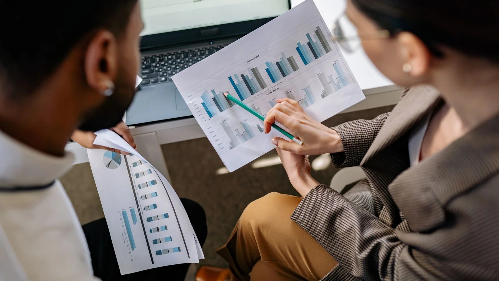 Two colleagues reviewing printed charts together, auditing which pages rank for a brand name