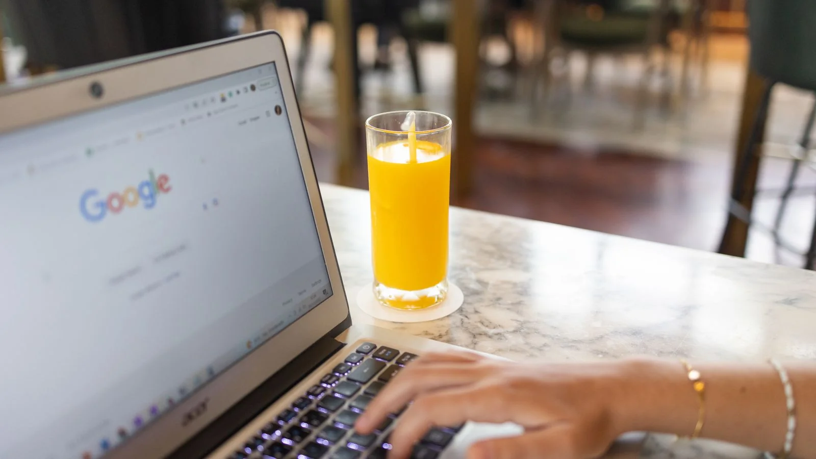 A person typing on a laptop with a search page open on the screen