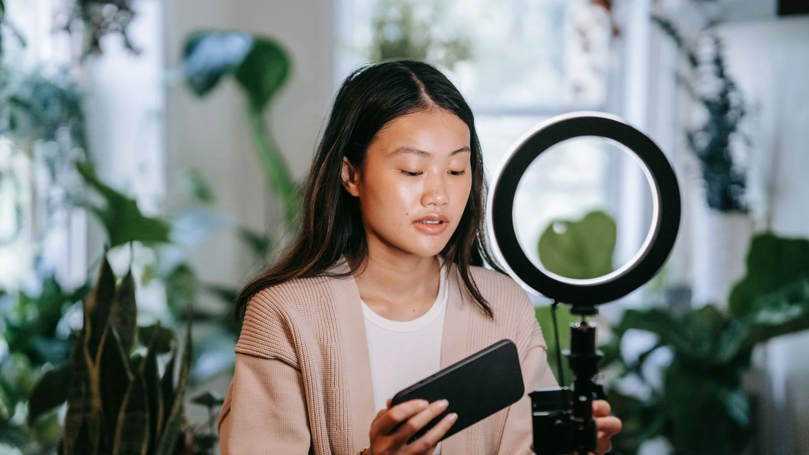 A creator adjusting a phone and ring light to record, the low-cost setup that carries a brow content calendar