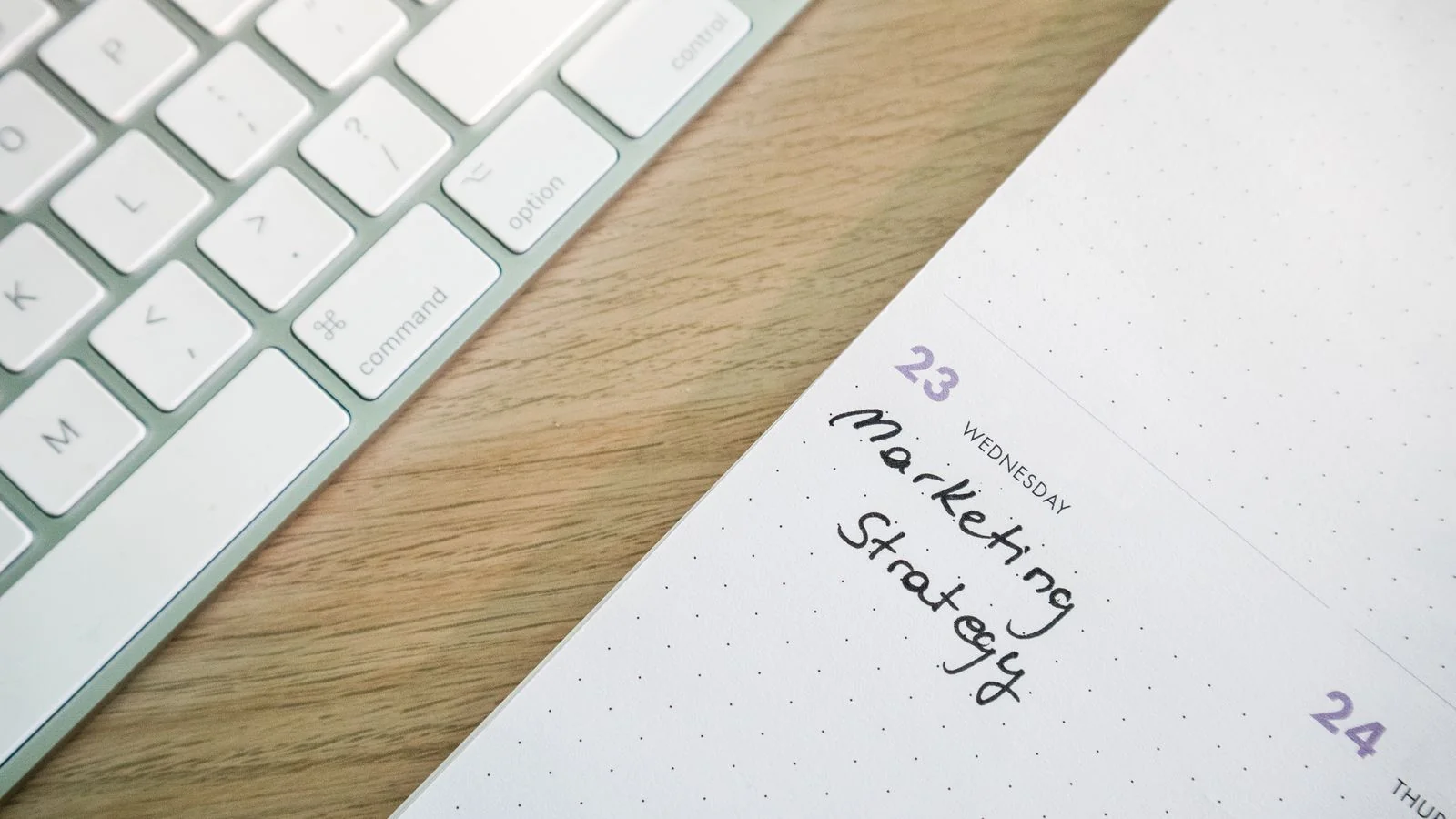 A desk with a keyboard and an open calendar marked with strategy notes, the six-week loop written down rather than improvised