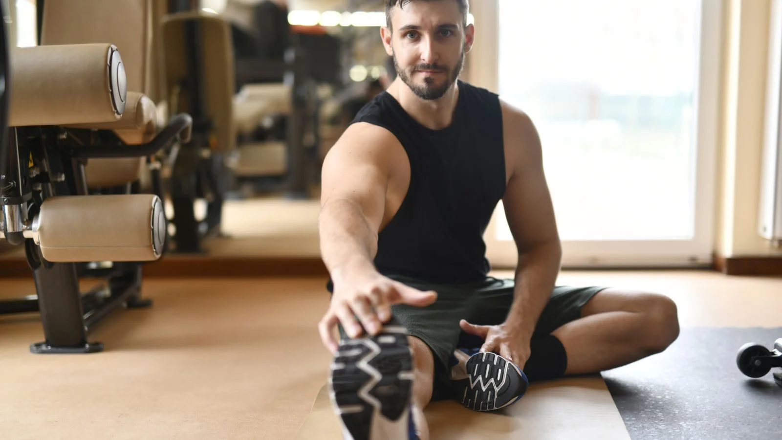 A man stretching on the floor of a modern gym, the recovery routine cryo studios compete with