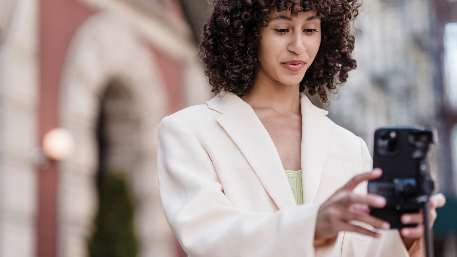 A woman preparing to record video on her phone in the street, the format that shows what writing cannot