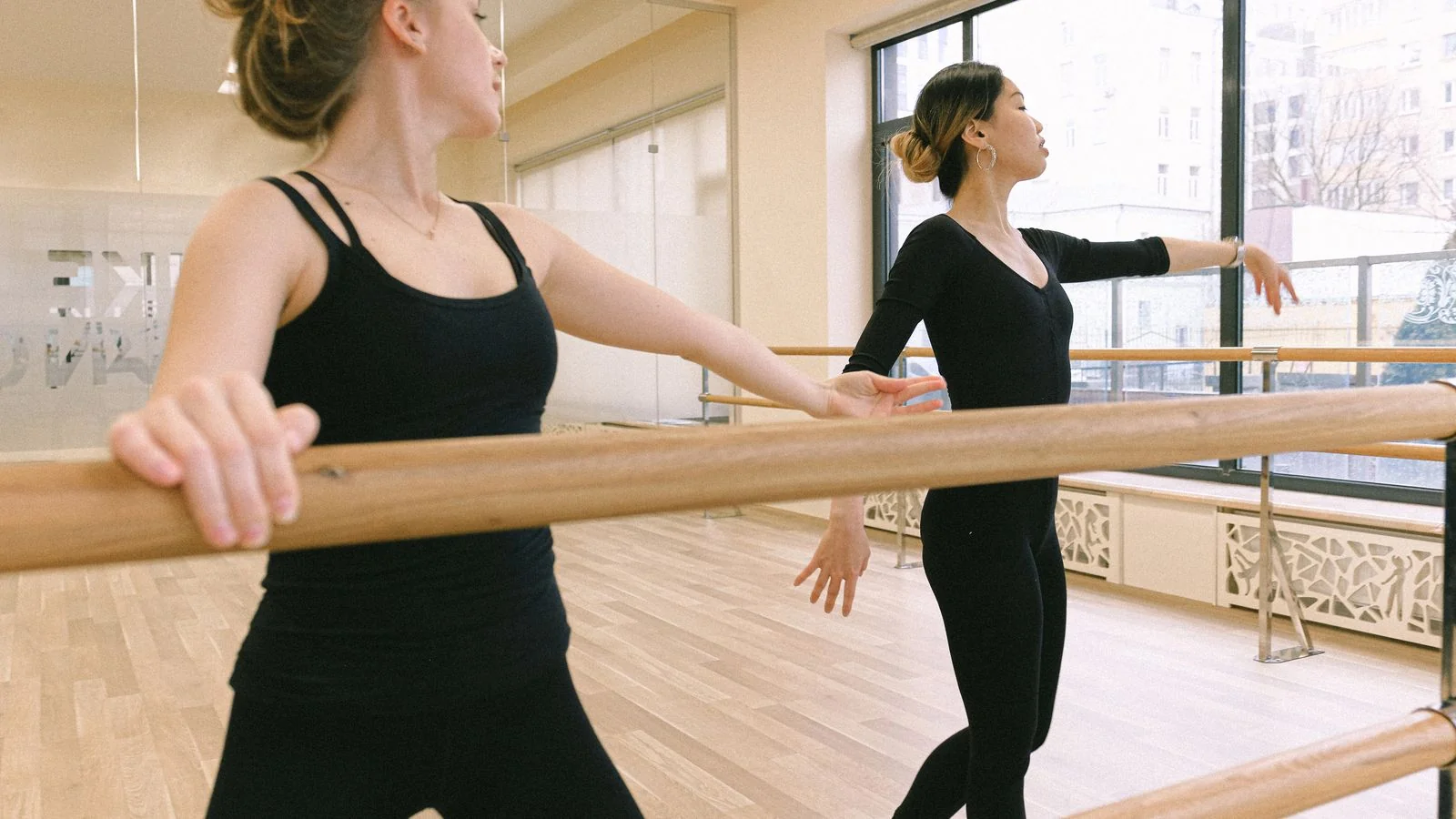 Two dancers working through a combination at the barre in an ordinary studio class