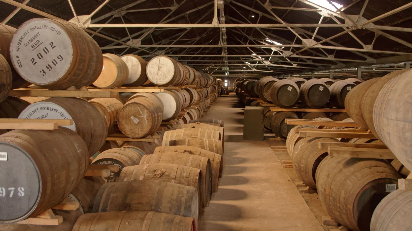 Barrels aging in rows inside a warehouse.