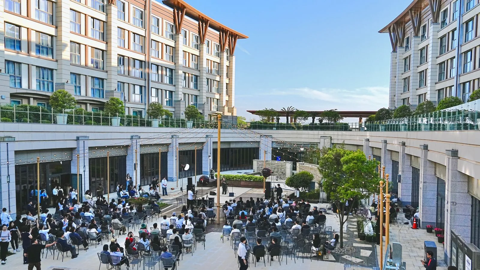 A large outdoor corporate event with attendees seated in a courtyard, the outcome a planner is trying to predict from your website.