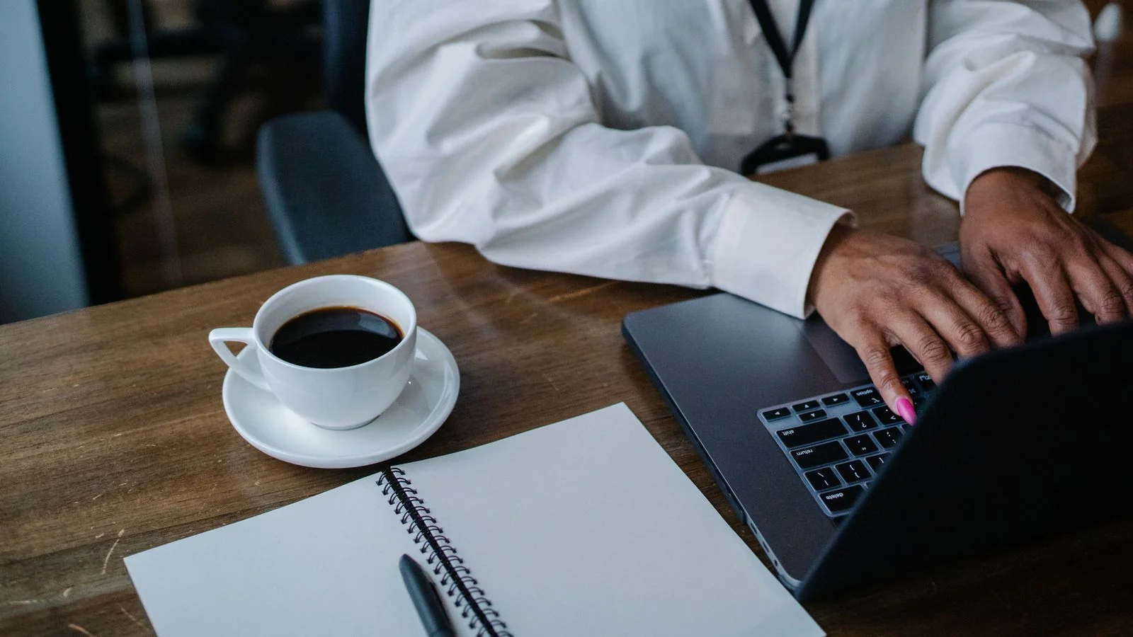 Hands typing on a laptop keyboard, drafting content for a search firm's audience.