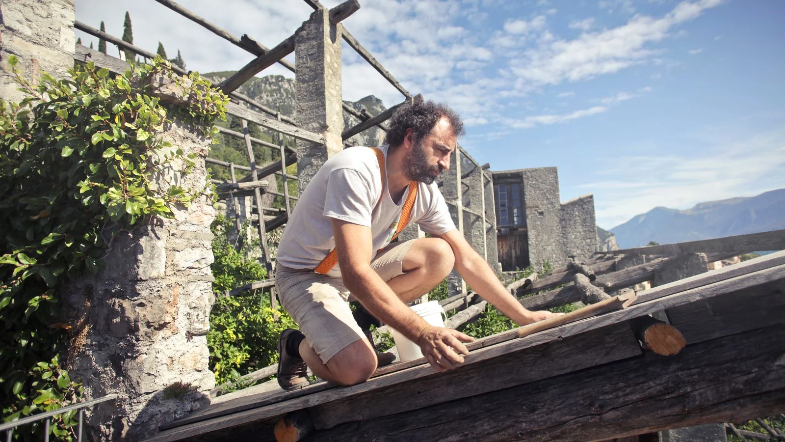A contractor works with wooden beams and framing on a bright, sunny day.