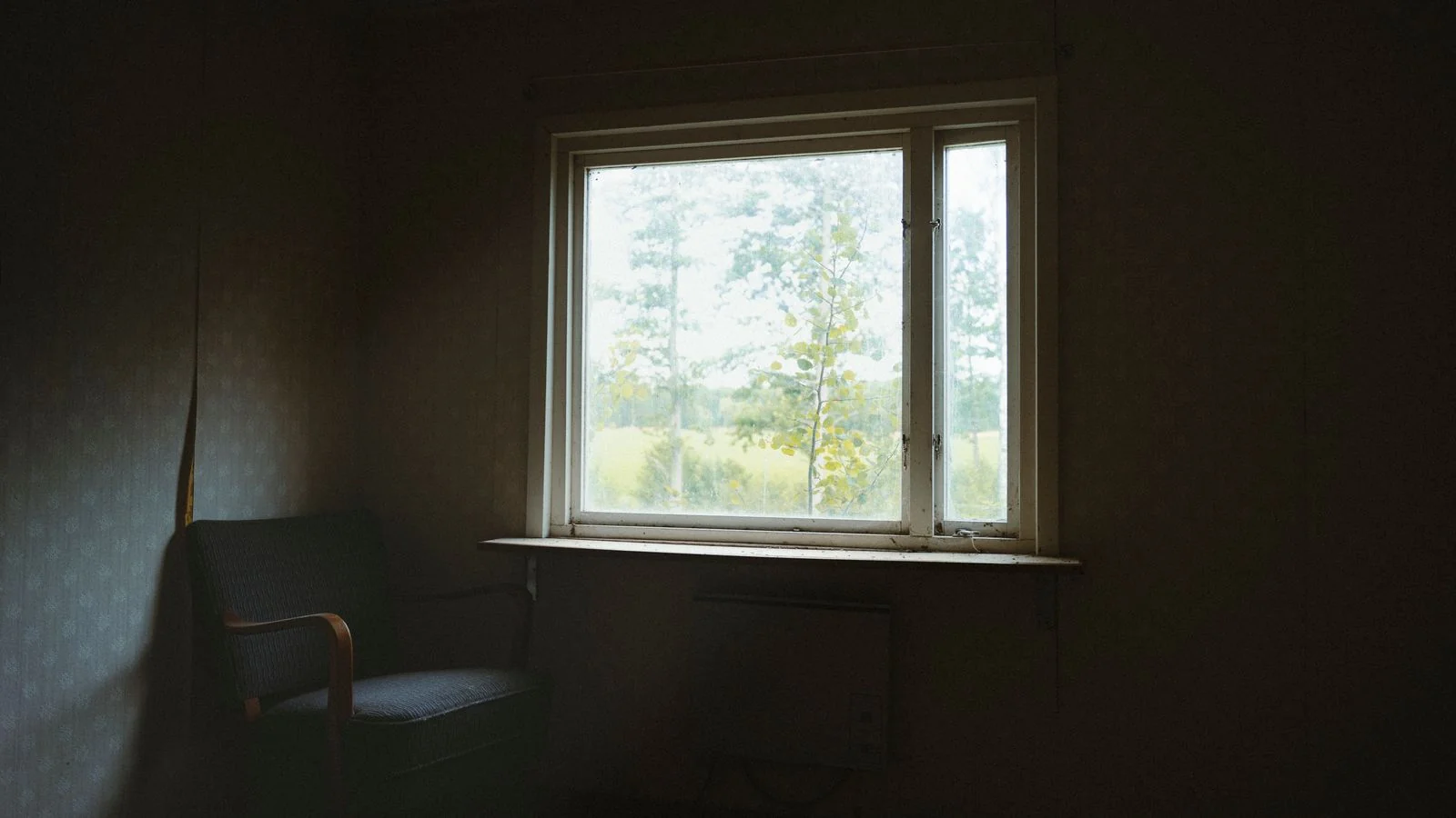 A dark, quiet room with a single chair facing a window, the stillness float centres sell and rarely describe