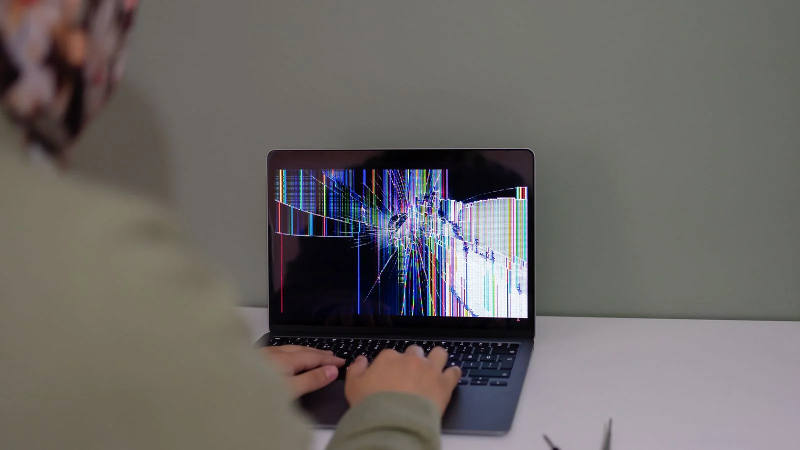 A person working at a laptop indoors, researching a problem before deciding to call anyone.