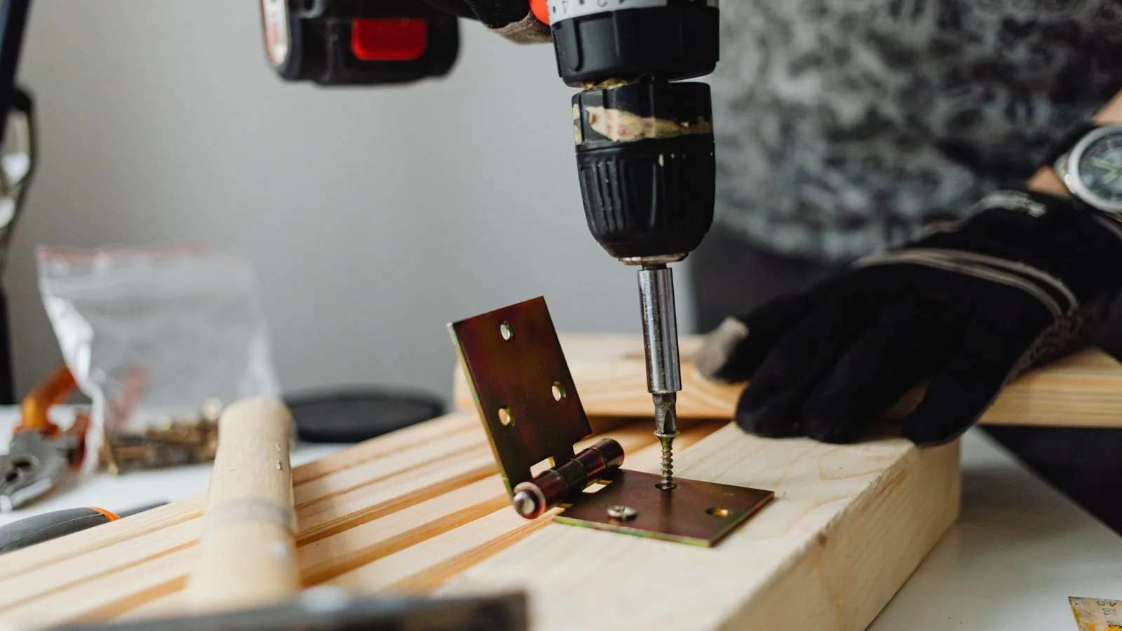 Close-up of a carpenter driving a screw into a door hinge, the kind of finished-job proof that builds trust.